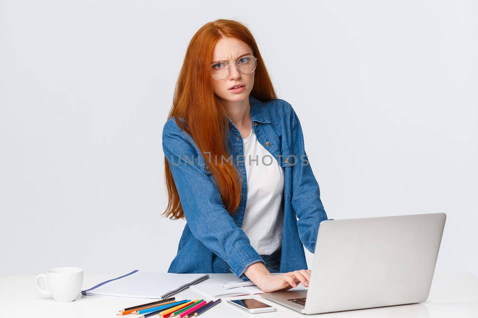 Stressed and annoyed serious-looking redhead hardworking woman with red hair, frowning staring pissed and distracted camera, having loads work, using laptop, standing white background.