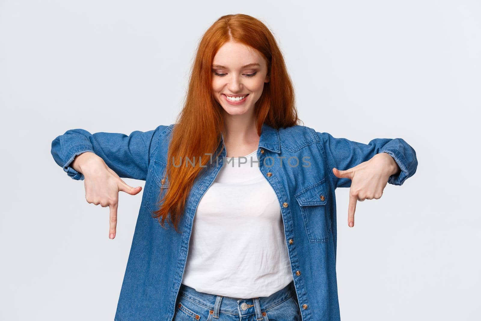 Happy, lovely young redhead woman picking presents for valentines day online, looking and pointing down, smiling delighted, found perfect discounts, good prices, awesome product, company service.