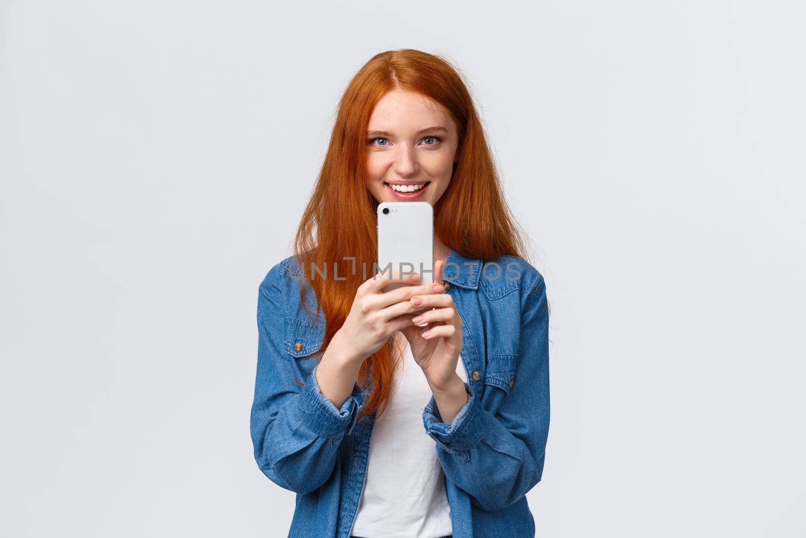 Friendship, togetherness and modern lifestyle concept. Cute redhead girl searching perfect angle, taking shot of friend on smartphone, phogotaphing, shooting something interesting.