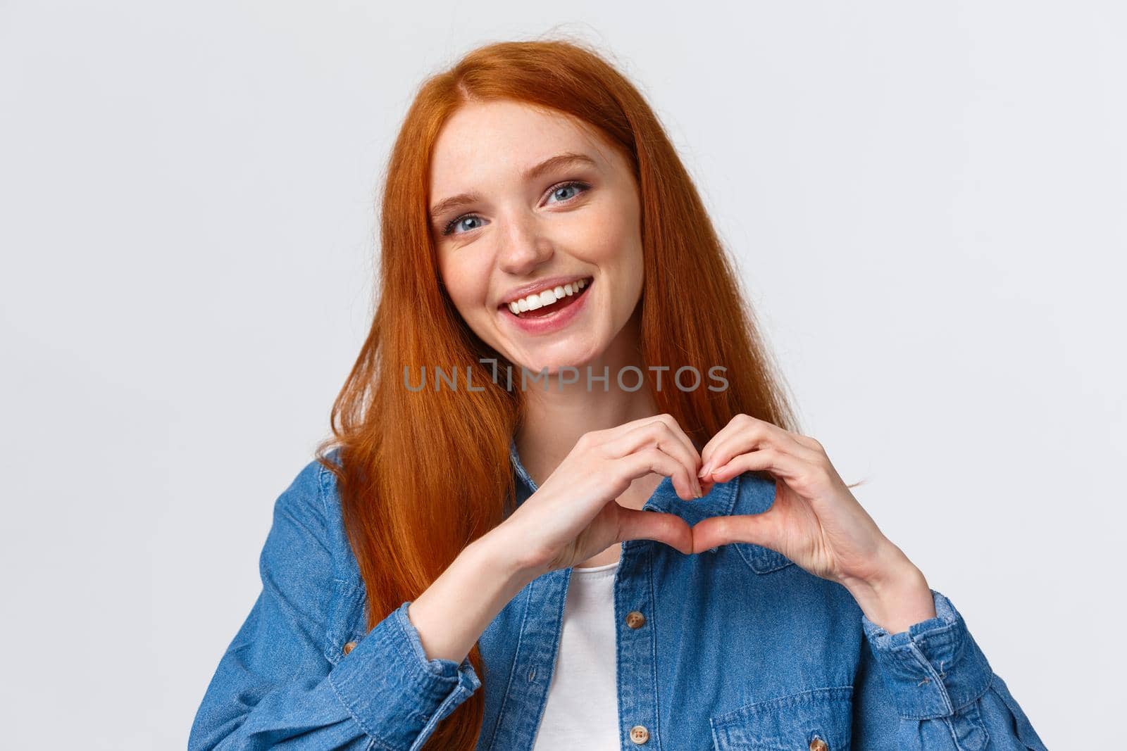 Happy valentines day, love. Cute and tender romantic redhead girlfriend showing heart sign, confess in sympathy, express passion or like, admire amazing artwork, appreciate, stand white background.