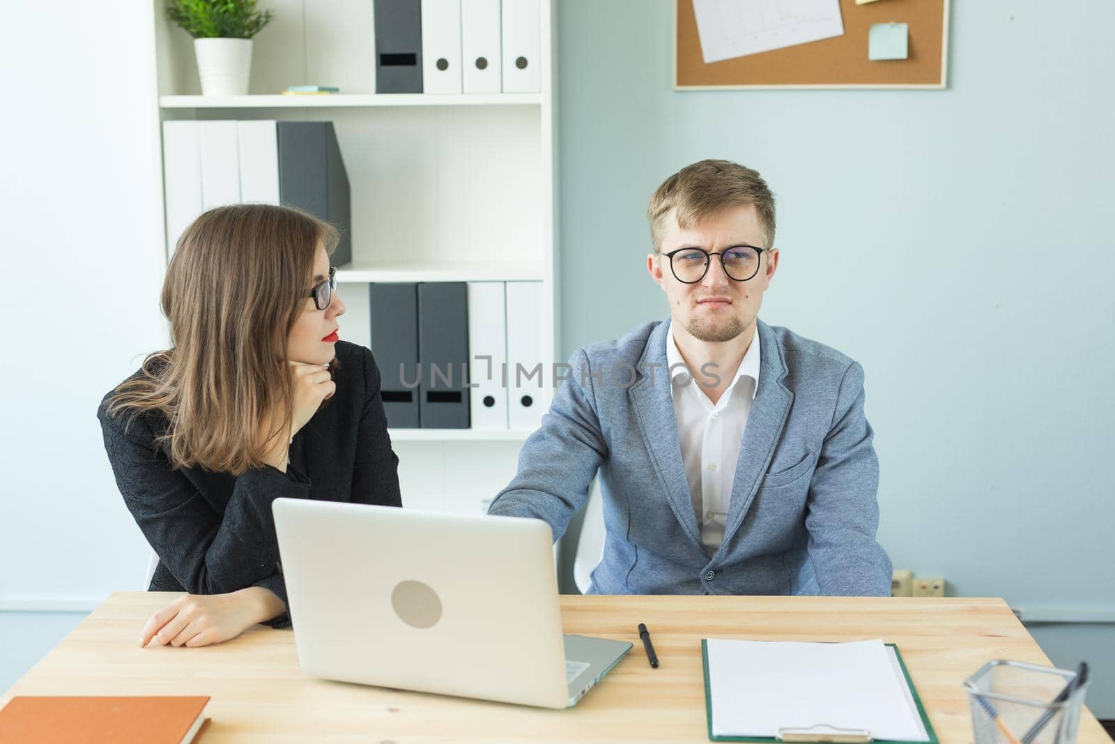 Business, emotions and people concept - Two angry and exhausted workers at working place. People wearing the packages on their heads with pictured emotions.