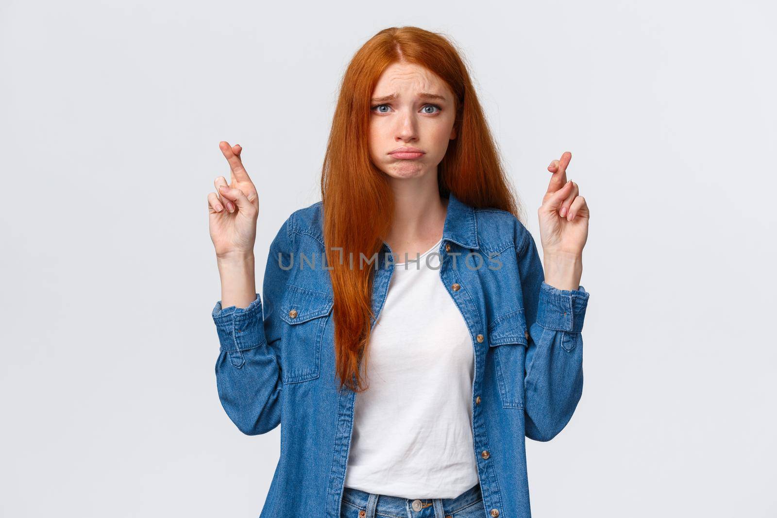 Girl hopes she passed exam. Worried and gloomy, hopeful redhead woman wishing dream come true, aspire something, pouting uneasy, cross fingers good luck, make wish over white background.