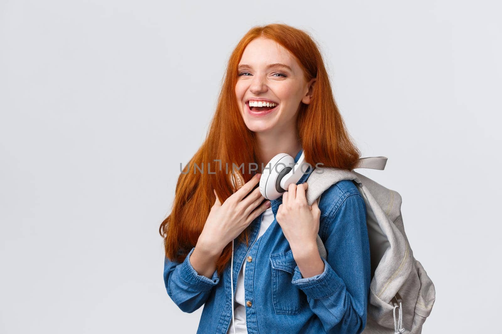 Education, student life and happiness concept. Cheerful good-looking redhead caucasian girl, college student with backpack and headphones over neck laughing smiling at camera.