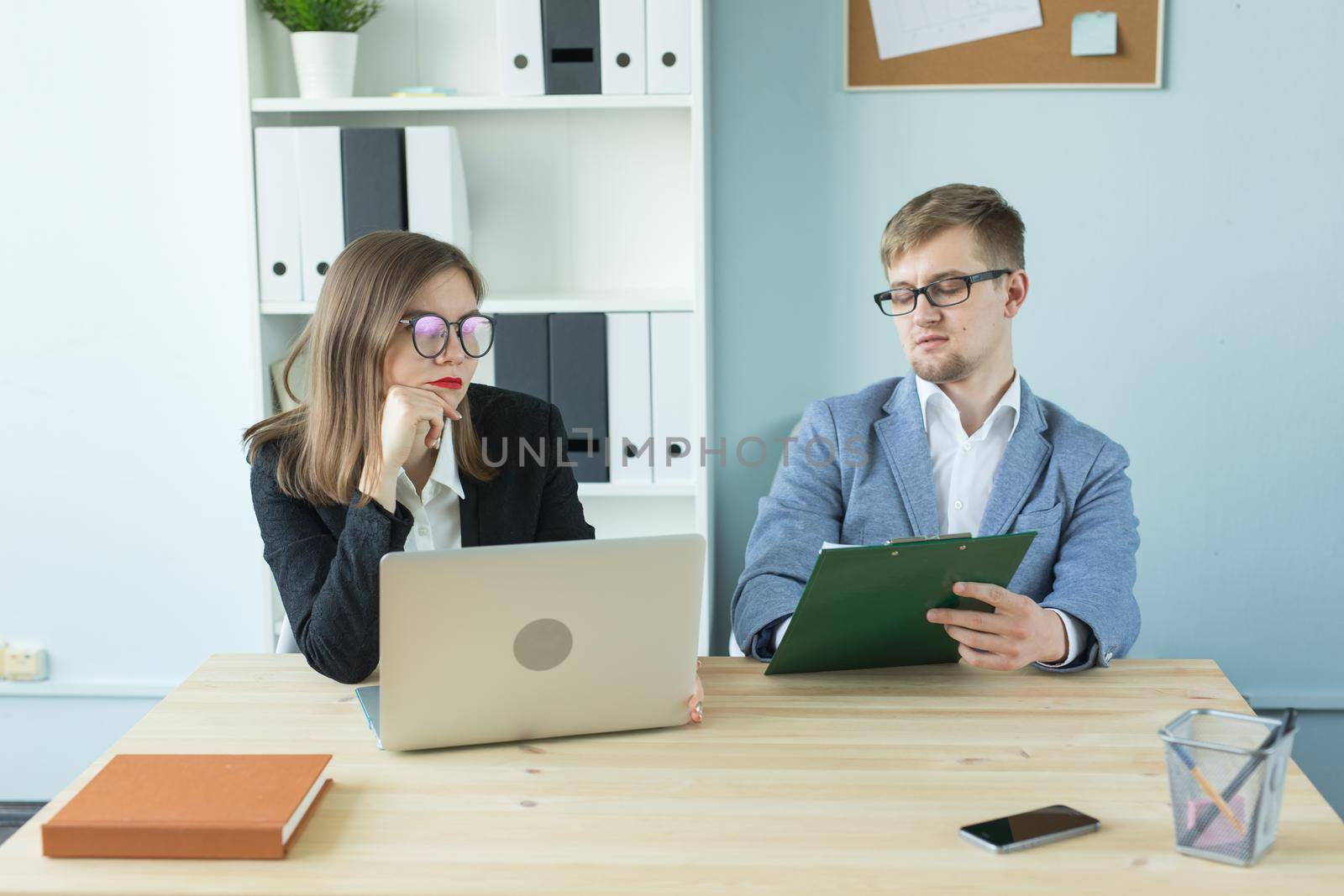 Business, teamwork and people concept - woman and man are working together in office by Satura86