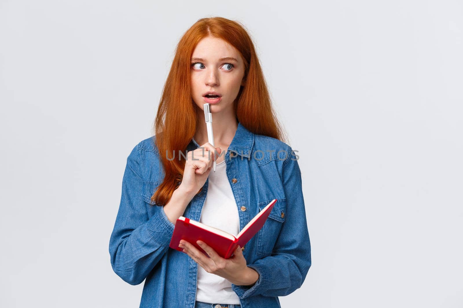 Talented, creative good-looking redhead woman writing poem, story, taking notes, prepare grocery list, gasping recall, remember something writing-down in notebook, white background.