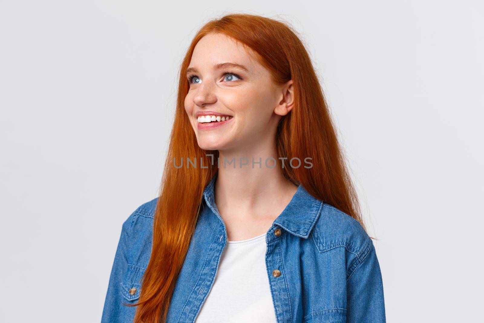 Close-up portrait dreamy and cute upbeat redhead woman seeing beautiful view, contemplate something wonderful, smiling and looking upper left corner delighted, white background.