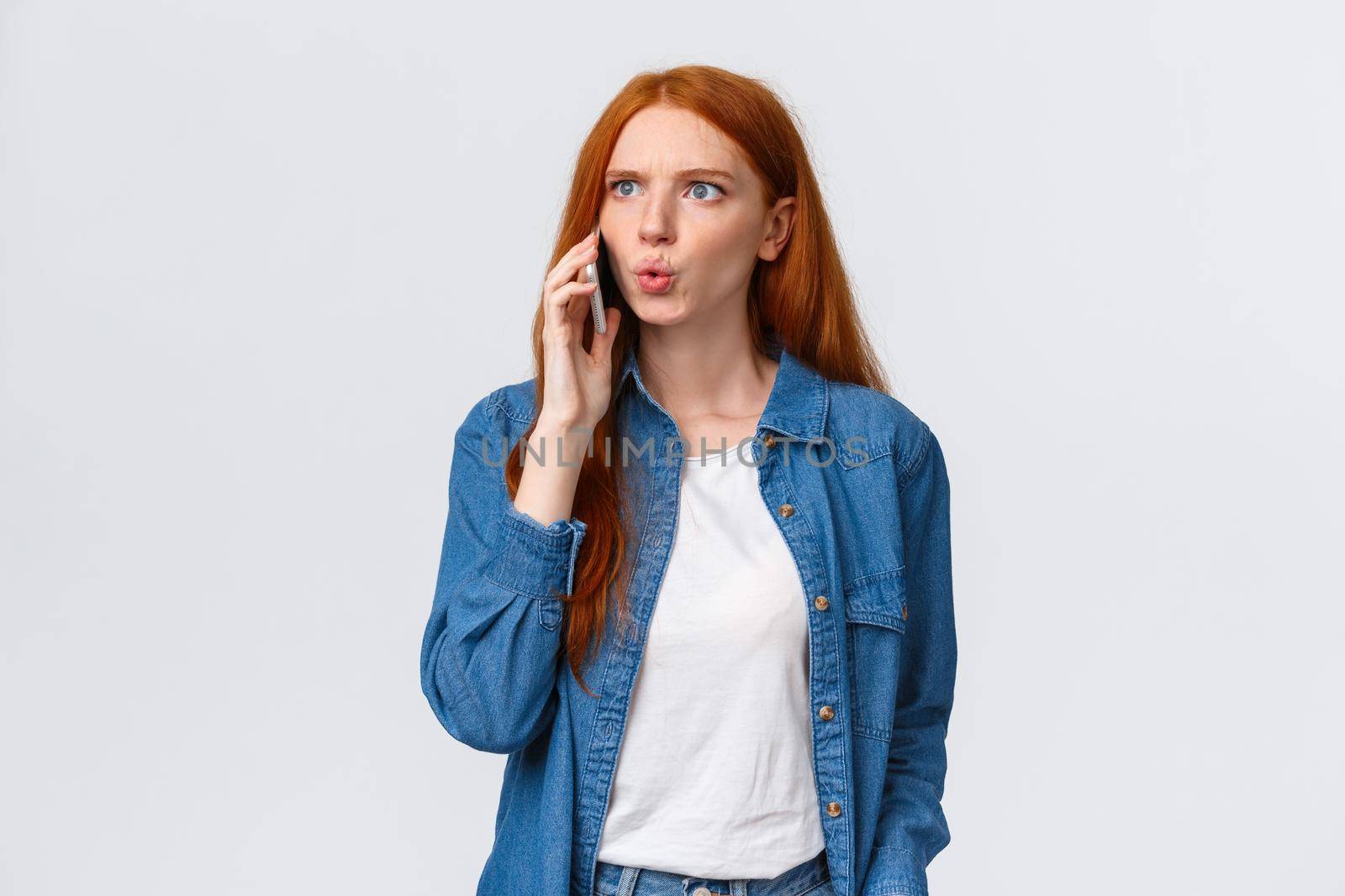 You say what. Intense and frustrated, confused redhead woman getting tensed and distressed hearing some bad news on phone, calling friend realise something awful happened, white background by Benzoix