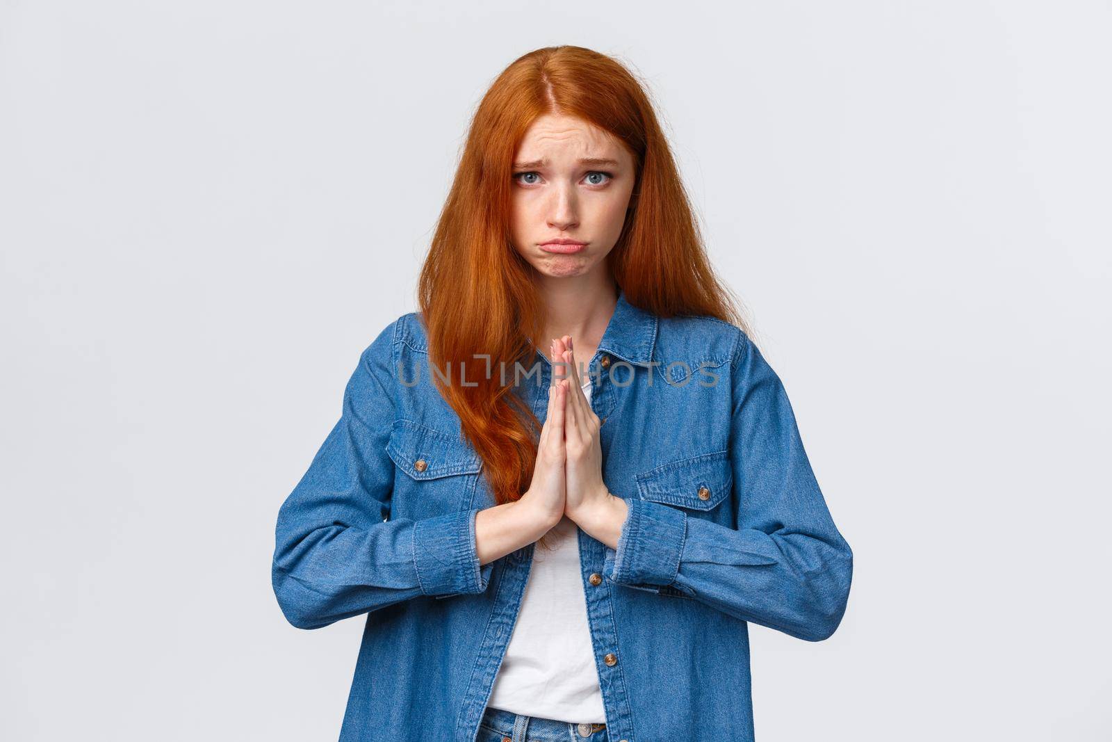 Waist-up portrait gloomy cute redhead girl begging aplogy, press hands together in pray, pouting and looking camera pleading, asking help, sorry, feeling regret for causing mess, white background.