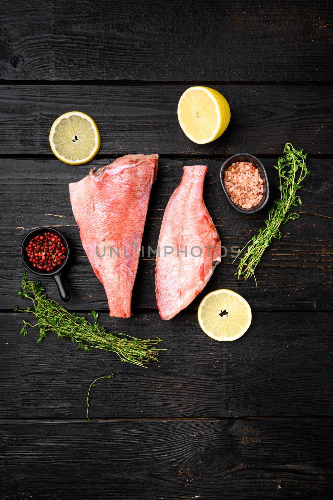 Whole raw fresh red perch or seabass fish set, on black wooden table background, top view flat lay, with copy space for text