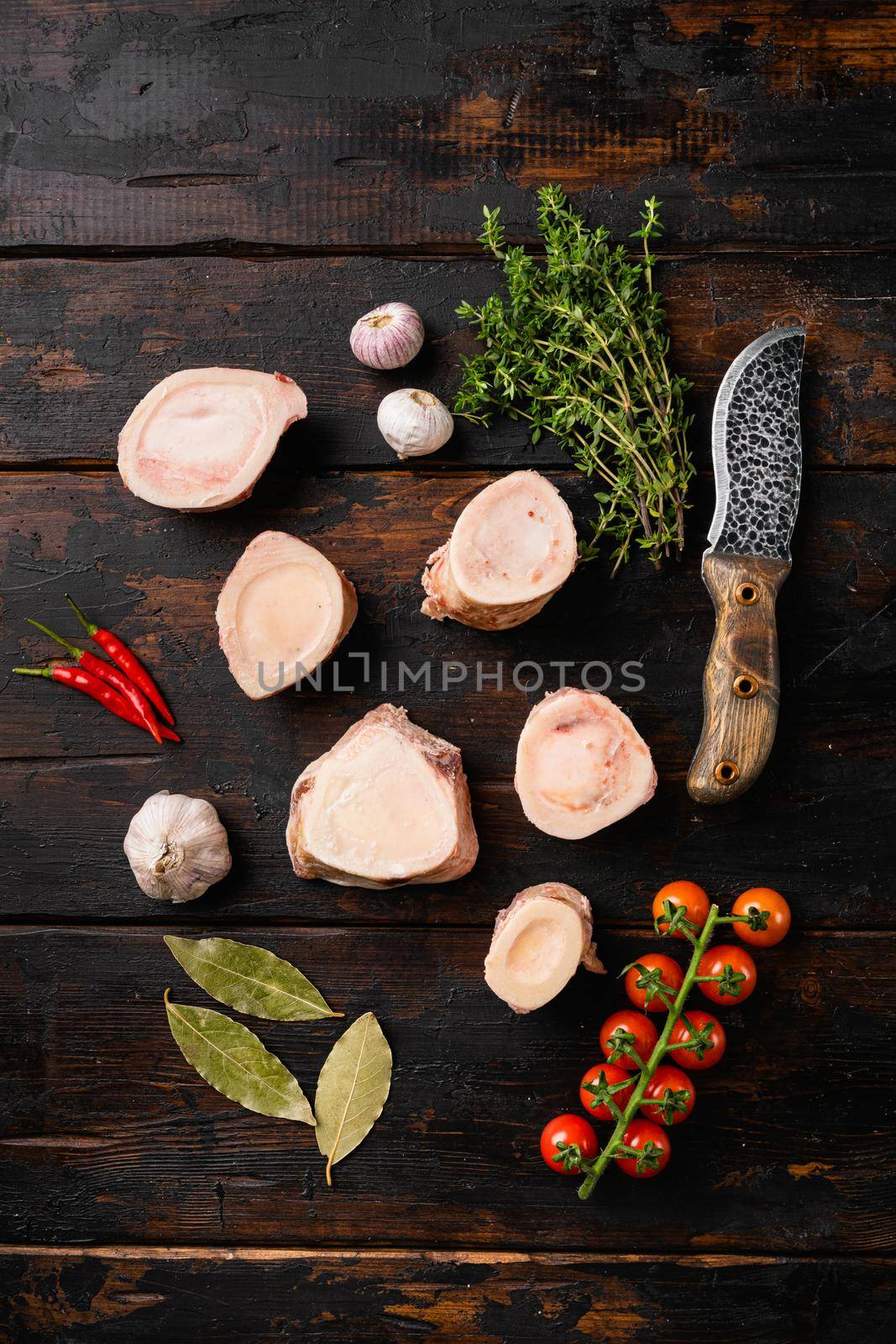 Raw calf bones set, on old dark wooden table background, top view flat lay