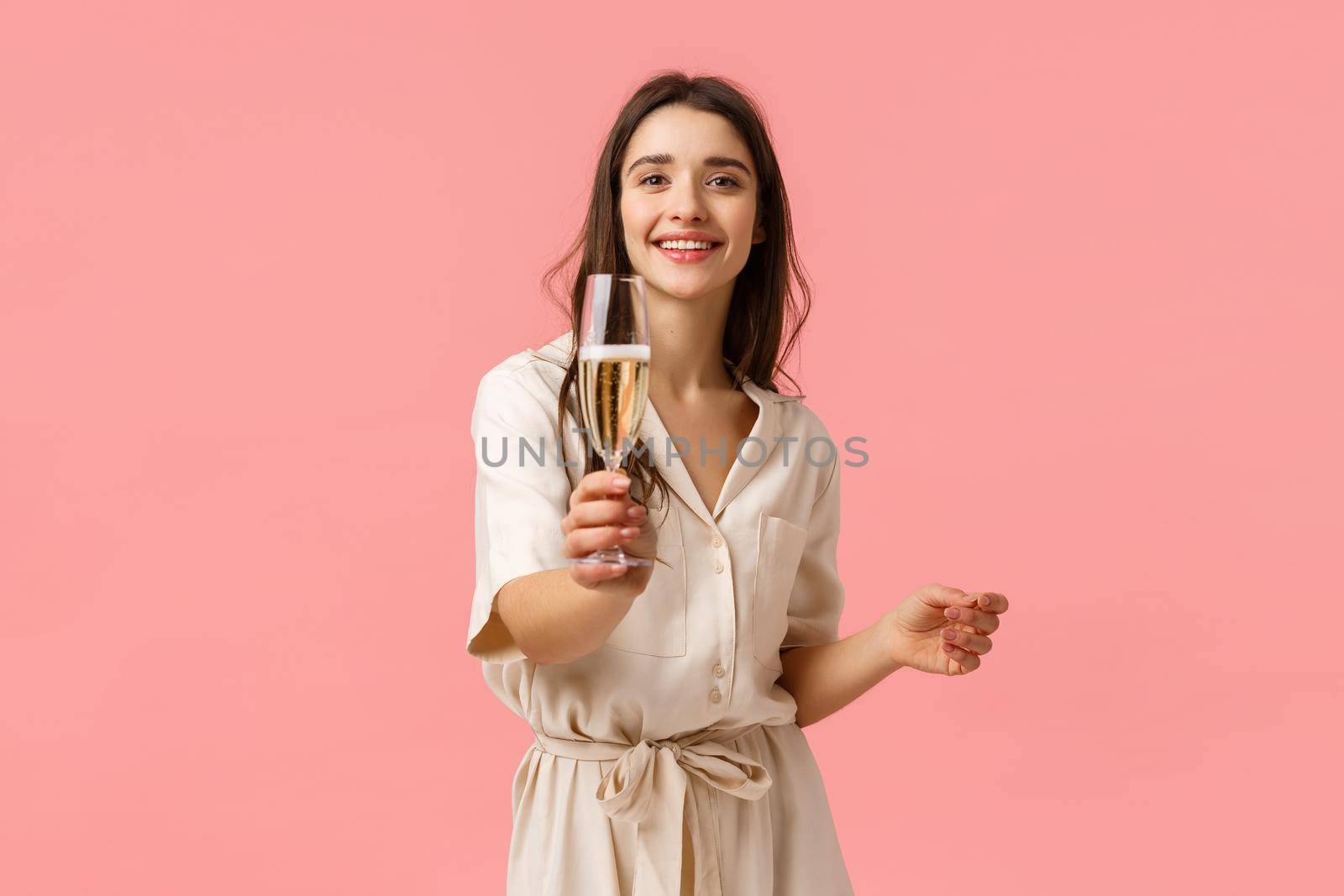 Here, make a toast. Cheerful romantic and alluring young girlfriend extending hand with glass, giving champagne to boyfriend, smiling joyfully, enjoying awesome party, pink background by Benzoix