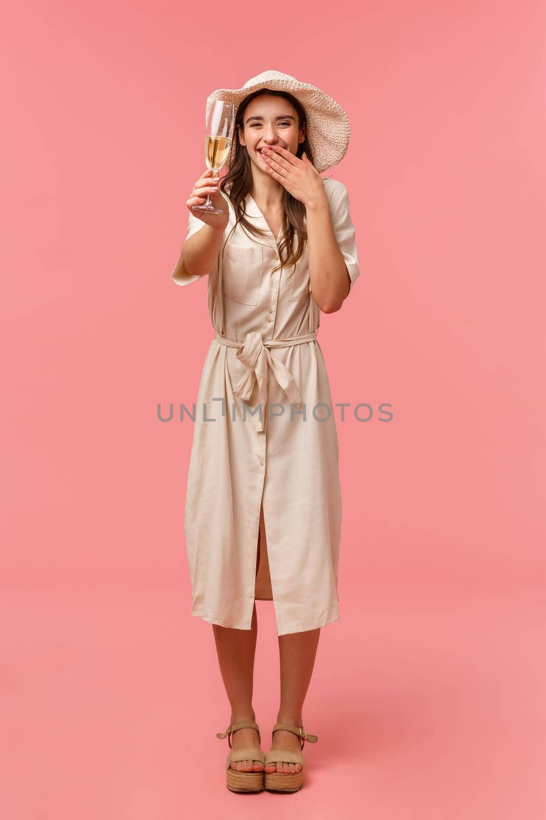 Full-length vertical portrait joyful happy and charismatic woman enjoying party, celebrating holidays with friends, raising glass, giving toast, say cheers and smiling, standing pink background.