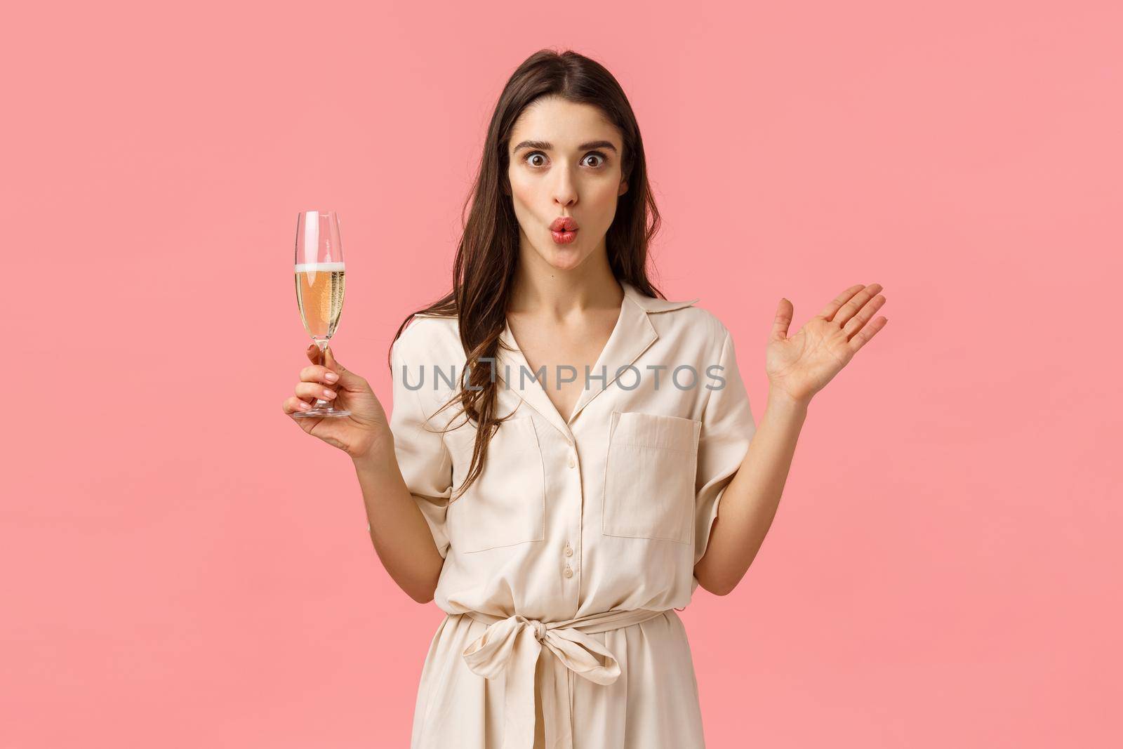 Wow wonderful news lets celebrate. Surprised and amused attractive brunette woman in dress, having fun partying, raising hands amazed, folding lips excited and holding glass champagne by Benzoix