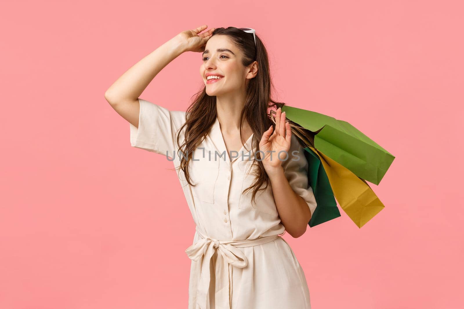 Romance, shoppaholic and women concept. Cheerful tender feminine woman holding shopping bags behind back, taking-off glasses and smiling happily left, enjoy browsing stores by Benzoix
