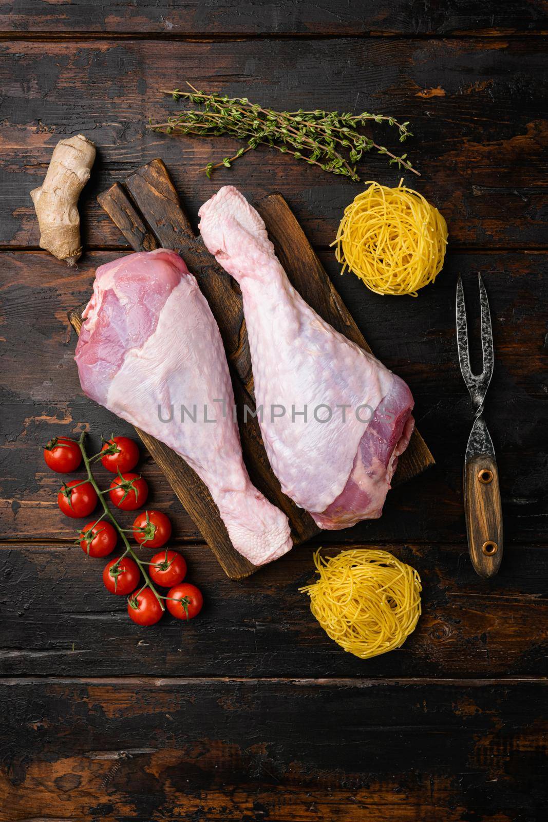 Raw turkey thigh with spices, on wooden cutting board, on old dark wooden table background, top view flat lay, with copy space for text by Ilianesolenyi