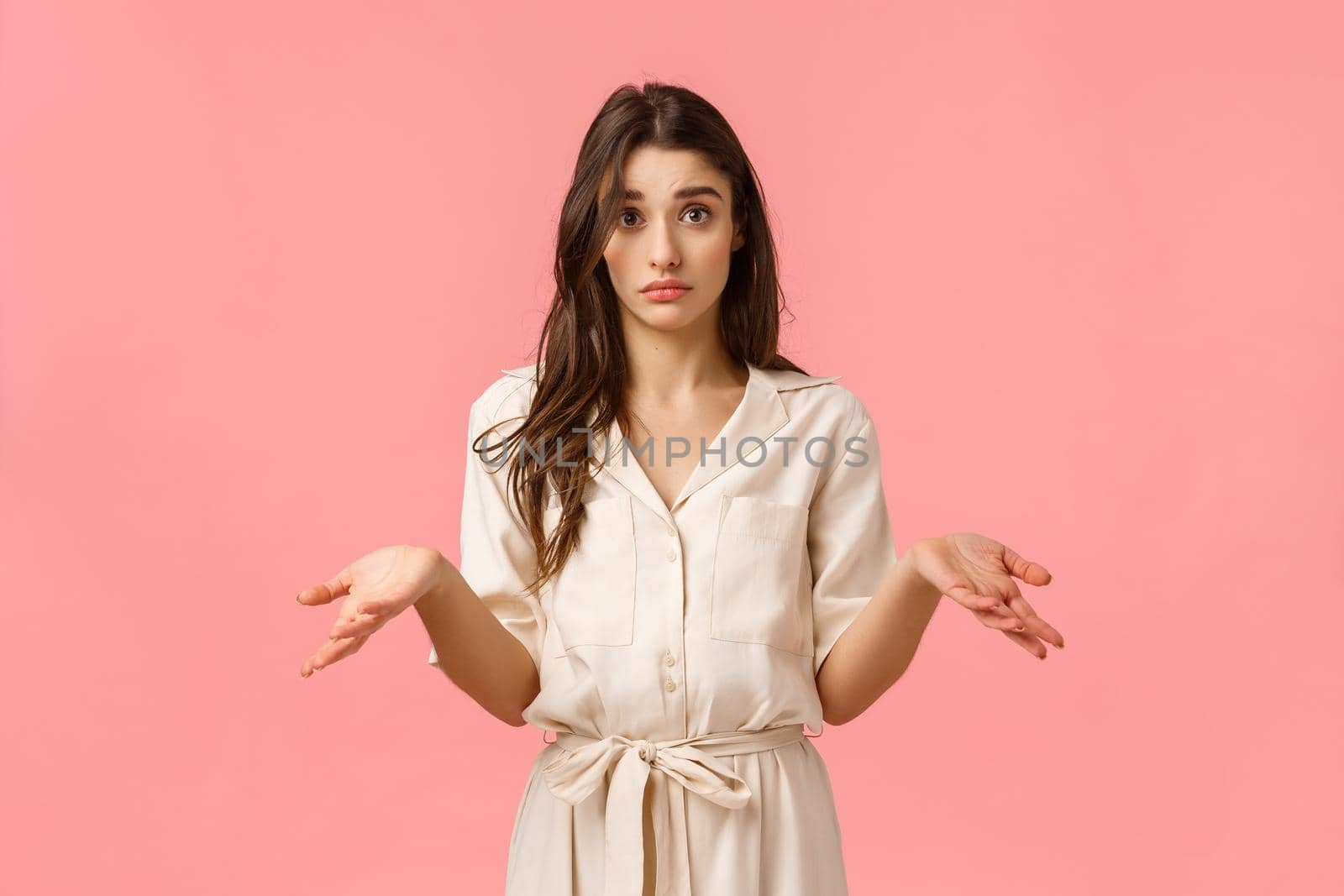 So what, I dont know. Silly and clueless uncertain cute, glamour girl in dress, shrugging and raise hands sideways confused, cant figure out what do, standing pink background unsure by Benzoix