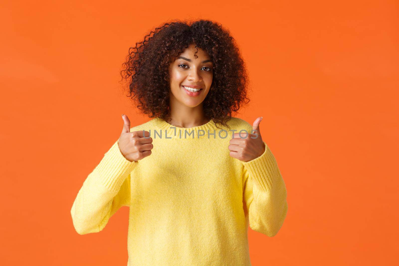 Waist-up shot cute supportive african-american woman feeling happy about great idea, shot thumb-up and smiling, agree with you, give positive answer, recommend product, orange background.