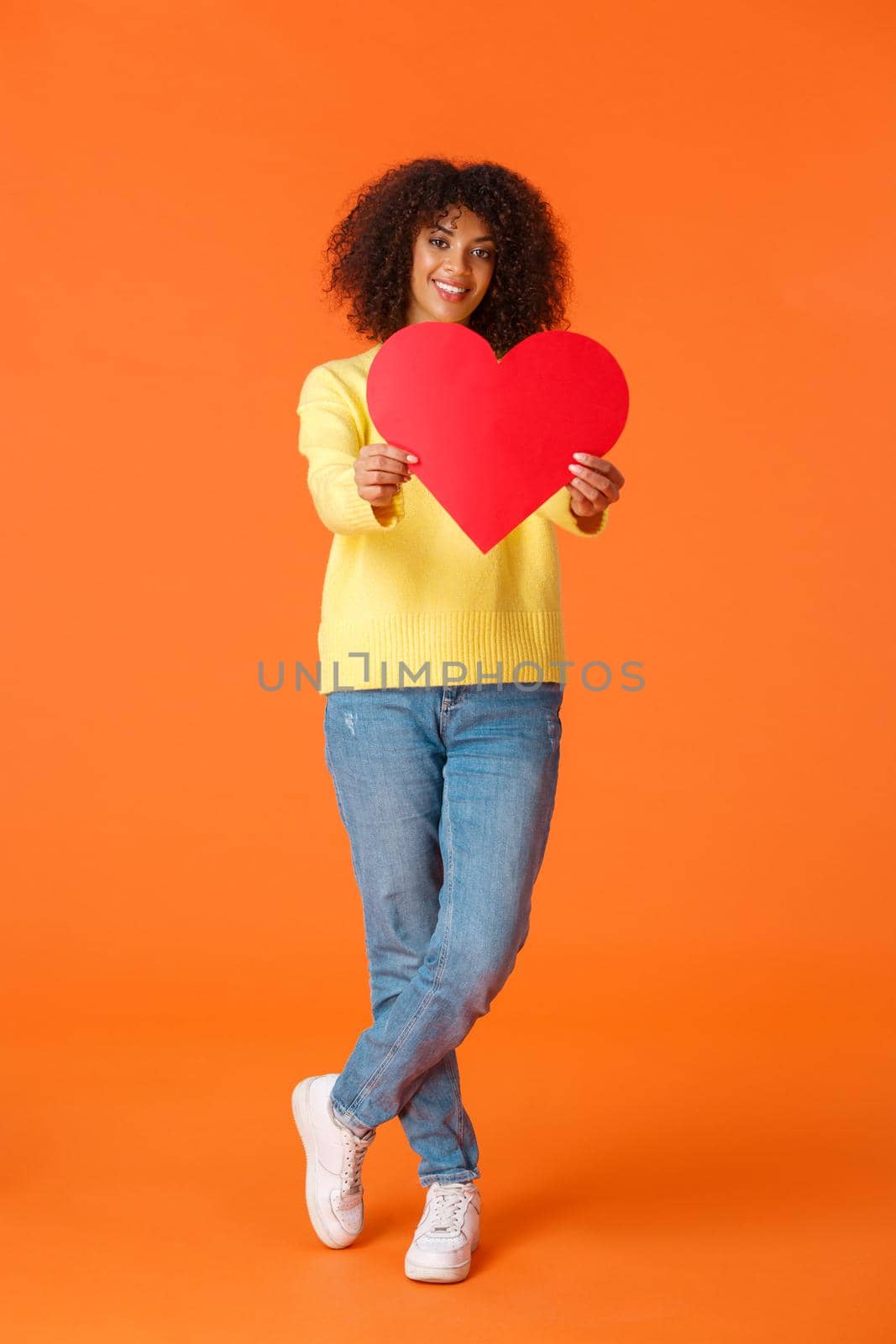 Full-length vertical shot romantic silly and cute african-amerian girlfriend, curly haircut, extend hands towards camera, give heart card and smiling, confessing love, searching soulmate.