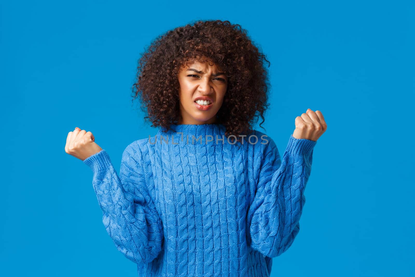 Failure, lifestyle and people concept. Upset and gloomy african american woman clench fists mad and grimacing, hearing bad news, lost bet, didnt win, standing distressed and tensed blue background by Benzoix