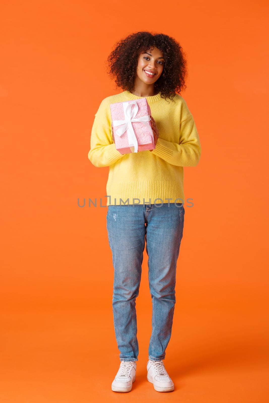 Full-length vertical shot cute and friendly african-american girl prepared gift for girlfriend, standing with wrapped present smiling tenderly camera, want congratulate with valentines day.