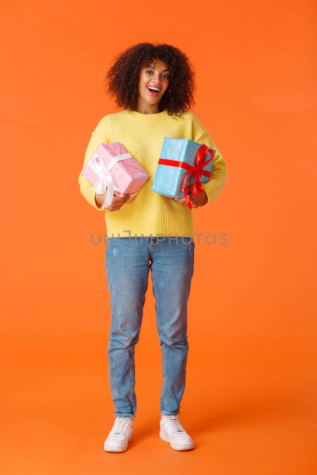 Full-length vertical shot excited cute happy african-american female received gifts for holidays, standing amused and delighted, holding two wrapped presents, orange background by Benzoix