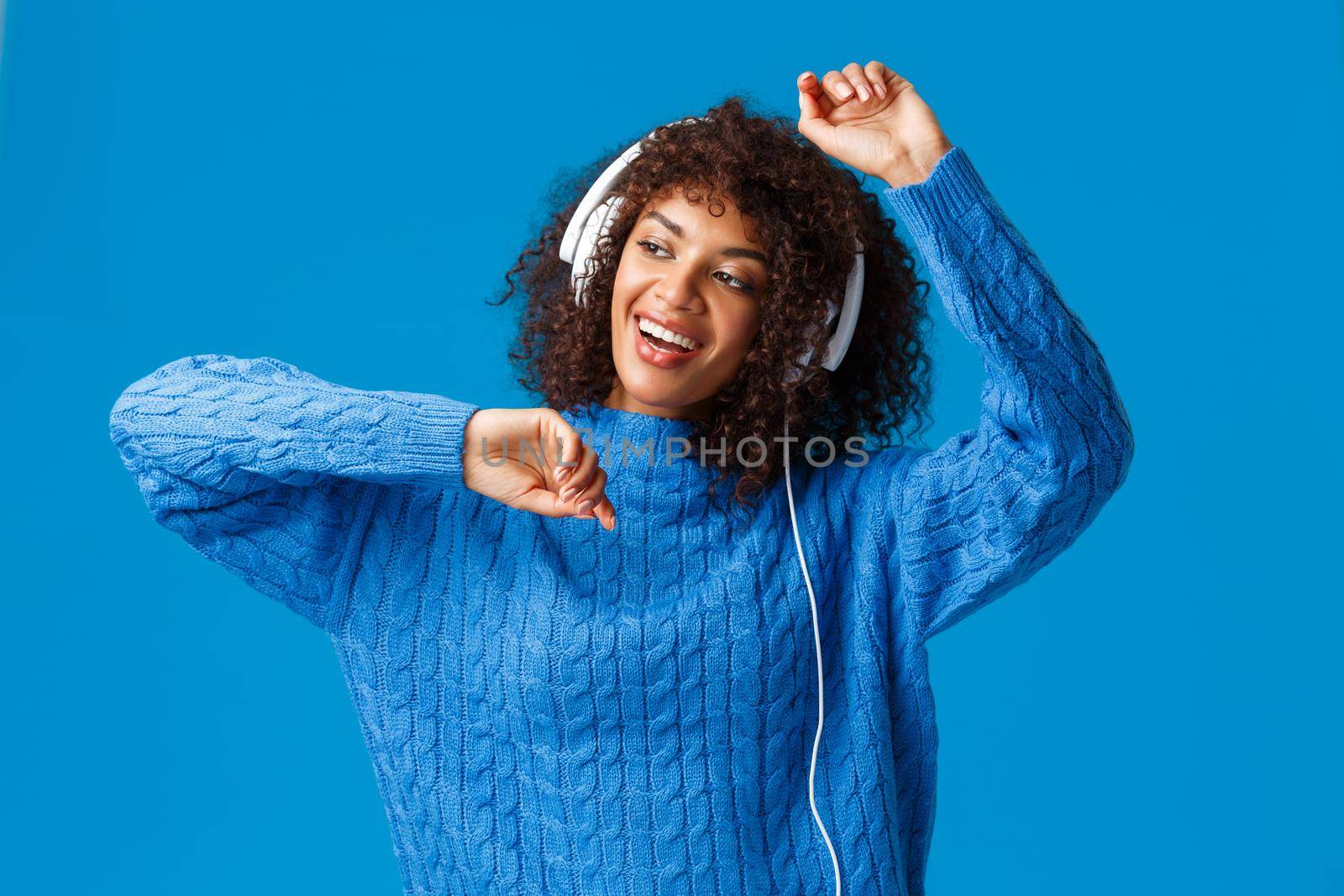 Lets get this party started. Carefree attractive african-american female having fun, enjoying awesome music sound, listen songs in headphones, dancing lift hands up relaxed, smiling upbeat.