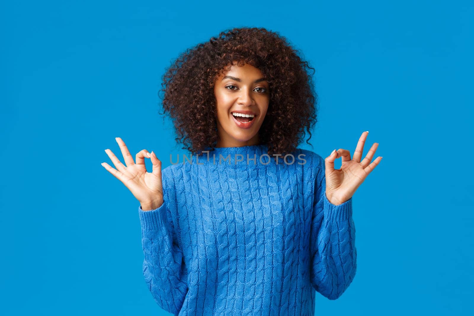 Alright it was awesome. Cheerful african-american woman having fun, rate good movie, give recommendation, smiling in approval, showing okay, good ok gesture and standing blue background.