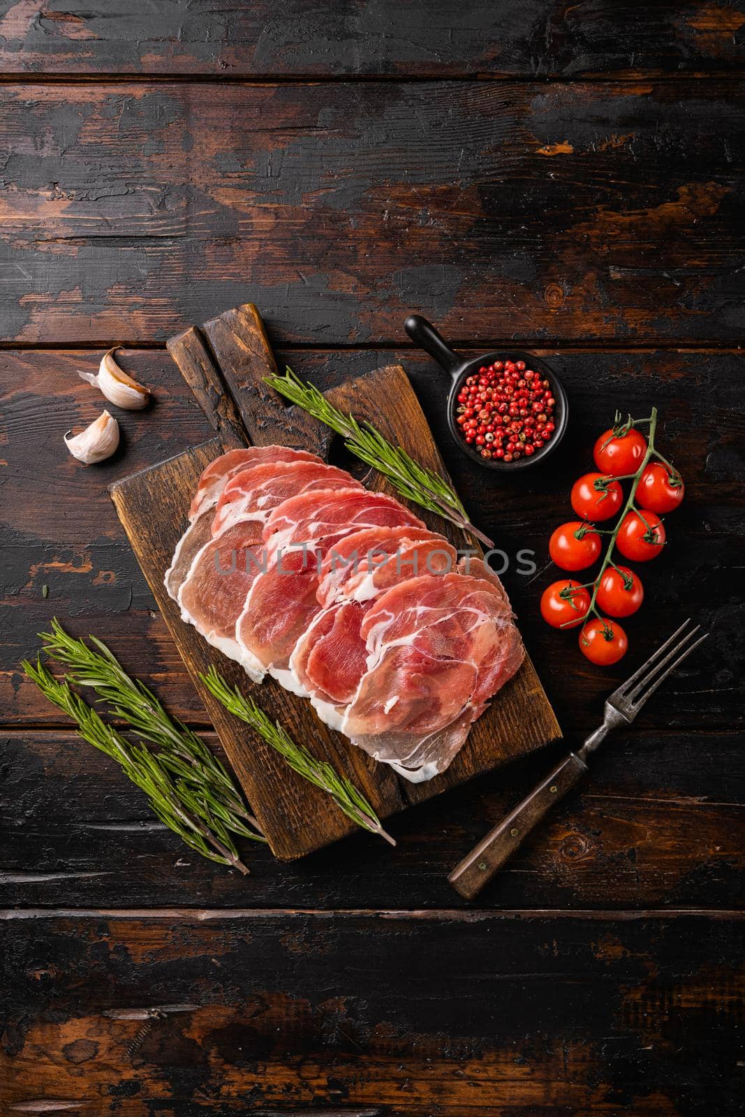 Dry Spanish ham, Jamon Serrano, on old dark wooden table background, top view flat lay, with copy space for text by Ilianesolenyi