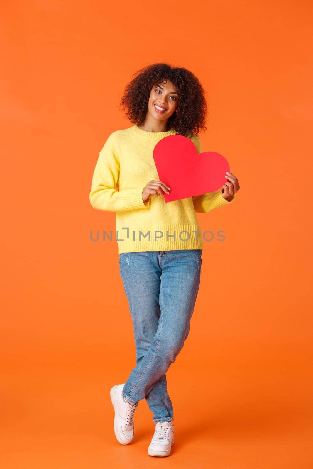 Full-length vertical shot attractive lovely smiling, romantic african-american girlfriend with afro, curly haircut, celebrating valentines day, holding big red cute heart and looking camera by Benzoix