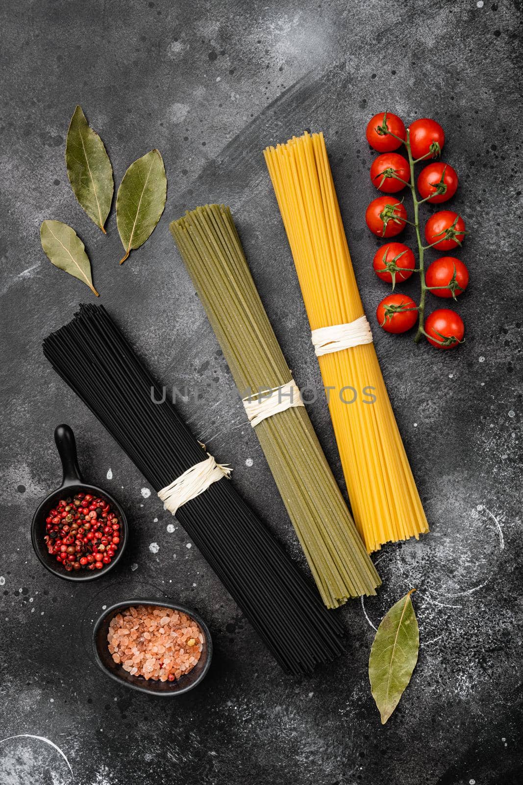 Dry colorful pasta spaghetti set, on black dark stone table background, top view flat lay