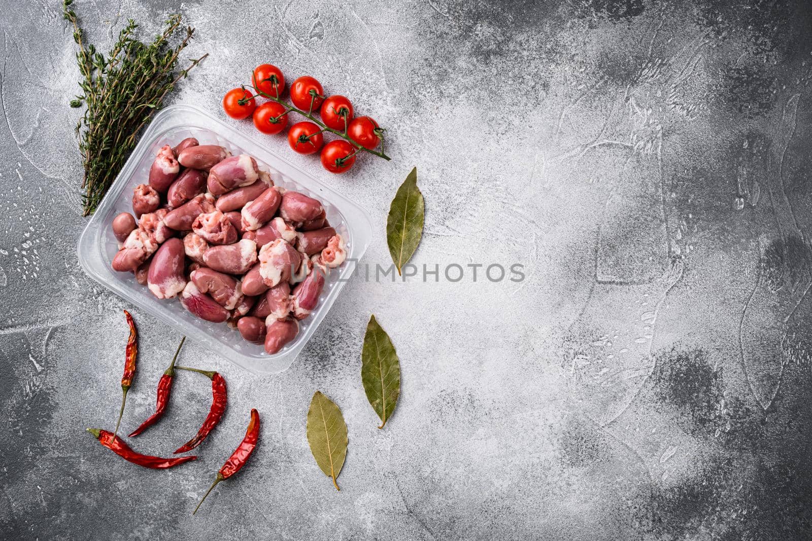 Raw fresh meat chicken hearts in plastic container set, on gray stone table background, top view flat lay, with copy space for text