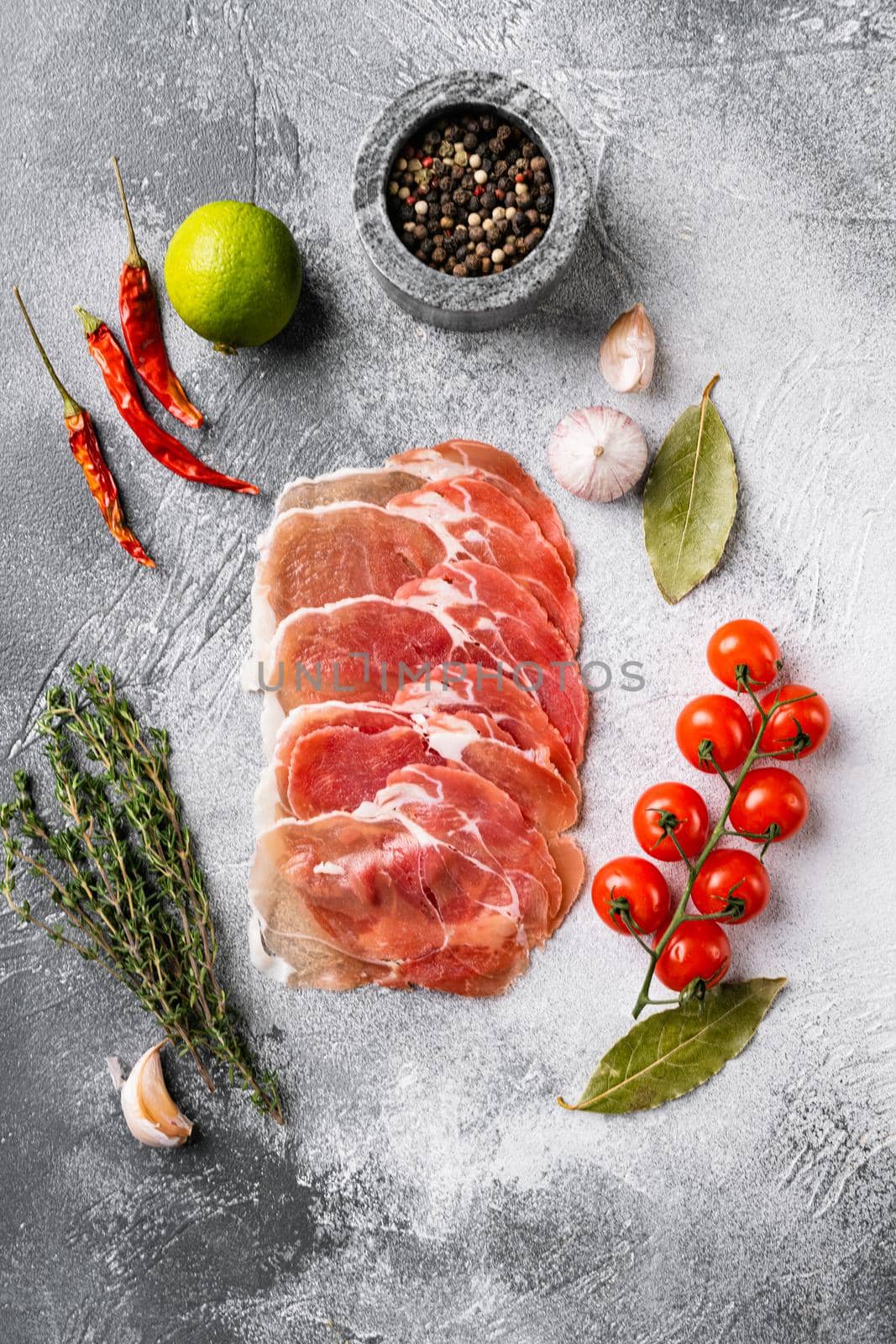Thin slices of prosciutto set, on gray stone table background, top view flat lay