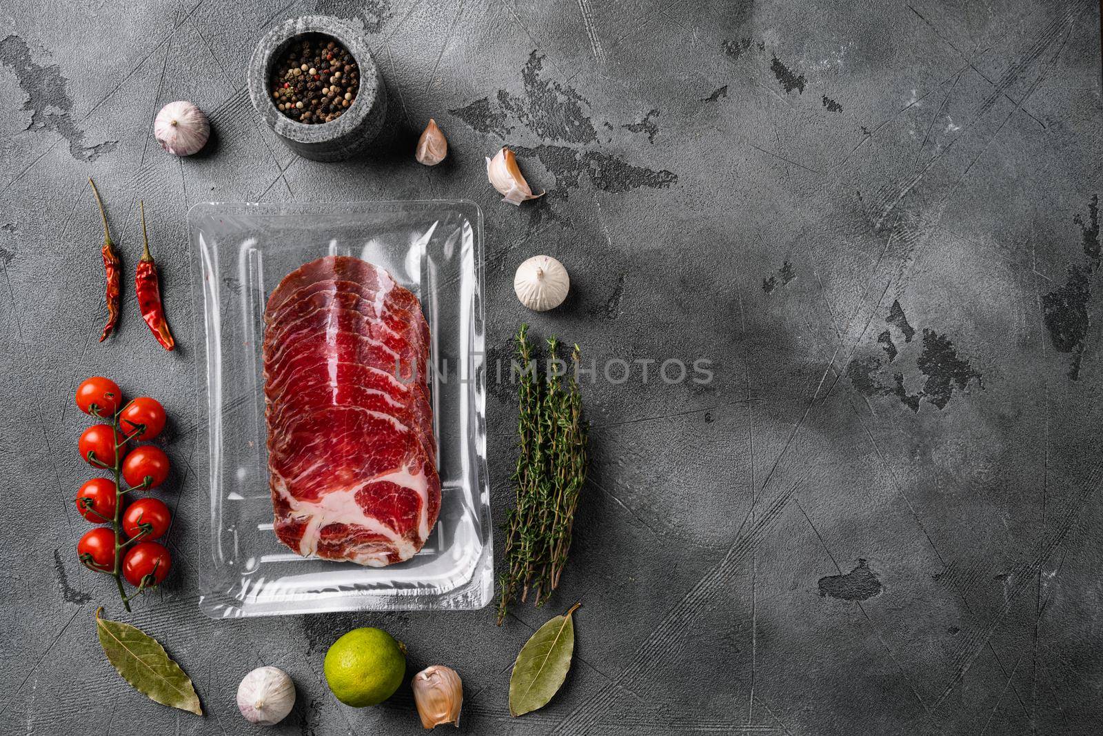 Italian dry cured ham vacuum pack set, on gray stone table background, top view flat lay, with copy space for text