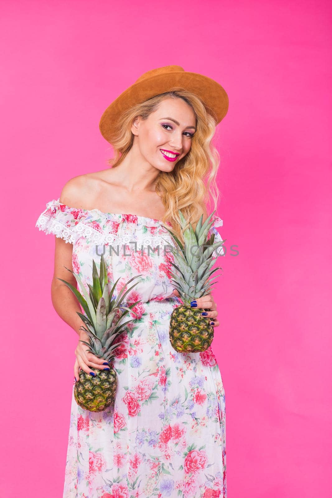 Portrait of funny woman and pineapple over pink background. Summer, diet and healthy lifestyle concept.