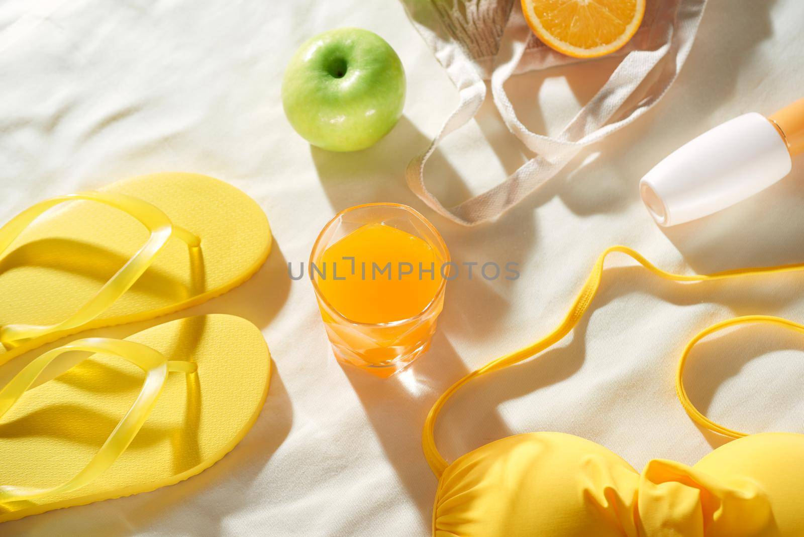 Summertime picnic on white background with fruit bag, flip-flop, sin cream and juice, flat lay