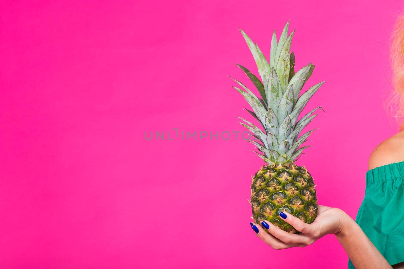 Closeup of woman and pineapple over pink background. Summer, diet and healthy lifestyle concept.