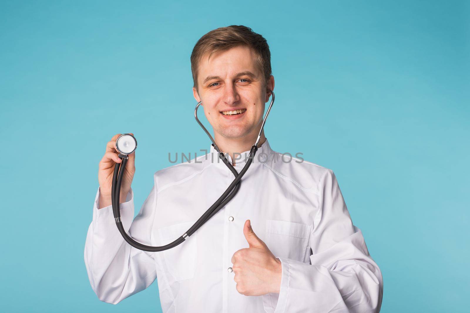 Doctor with stethoscope showing thumbs up over blue background by Satura86