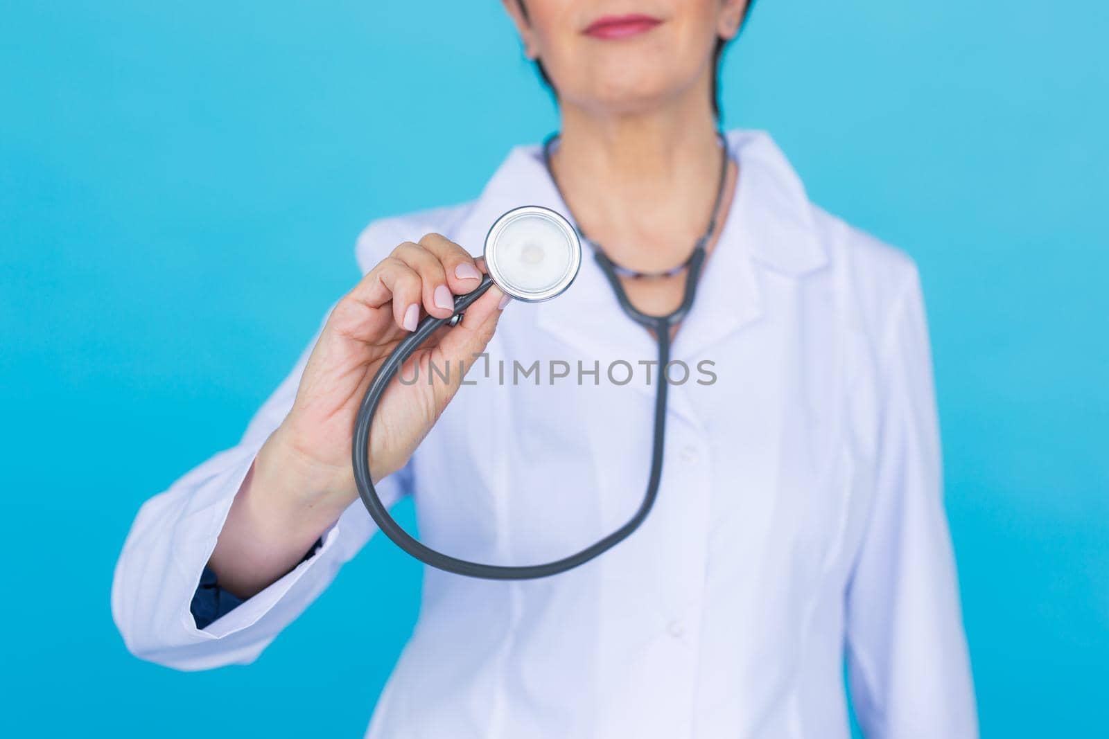 Doctor with stethoscope, close up over blue background.