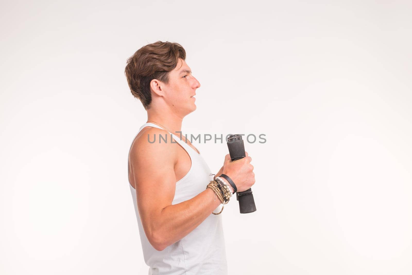An attractive sporty man shows his biceps and smiling on white background.