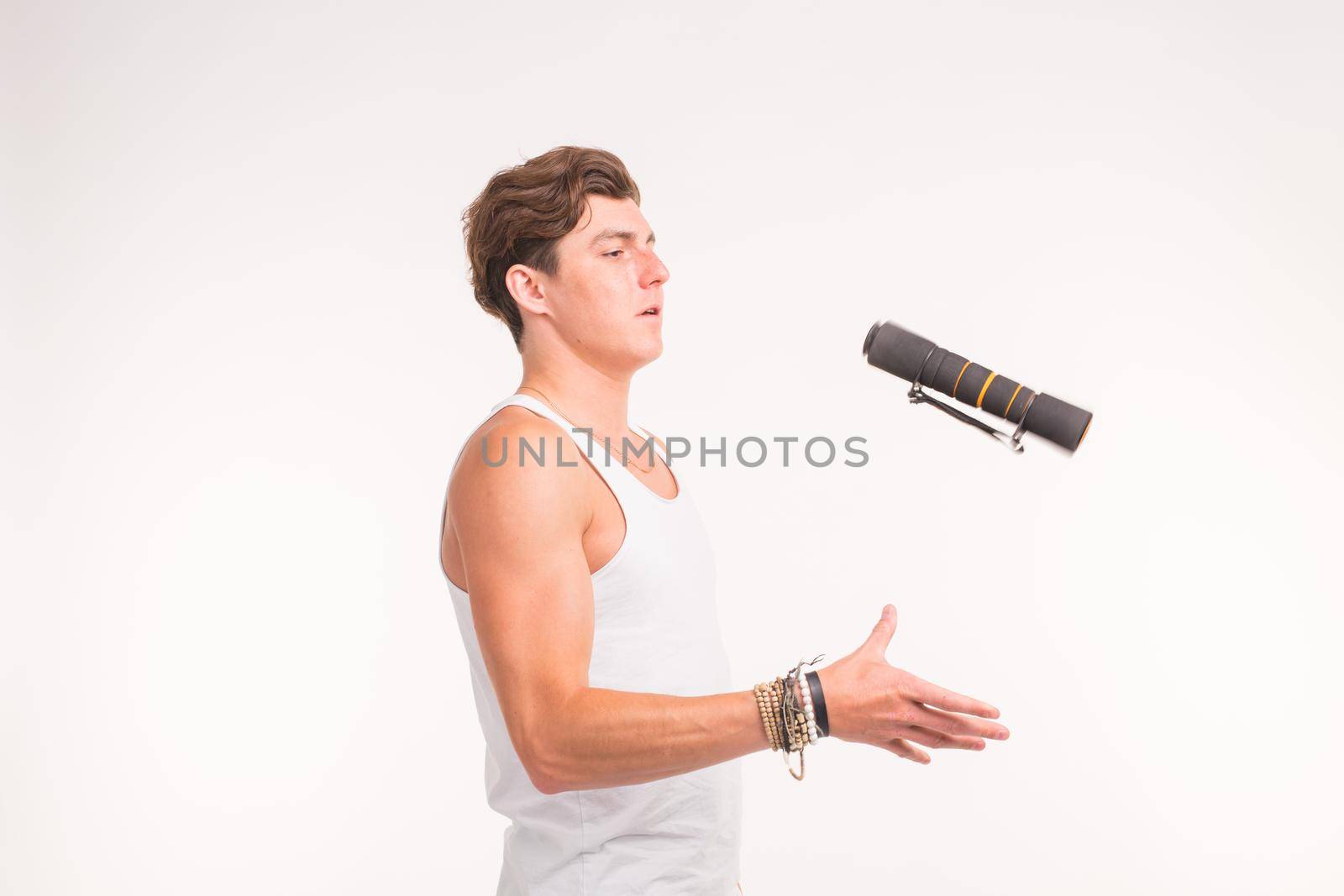 Expression, fitness and people concept - Handsome man throwing up a dumbbell over white background.