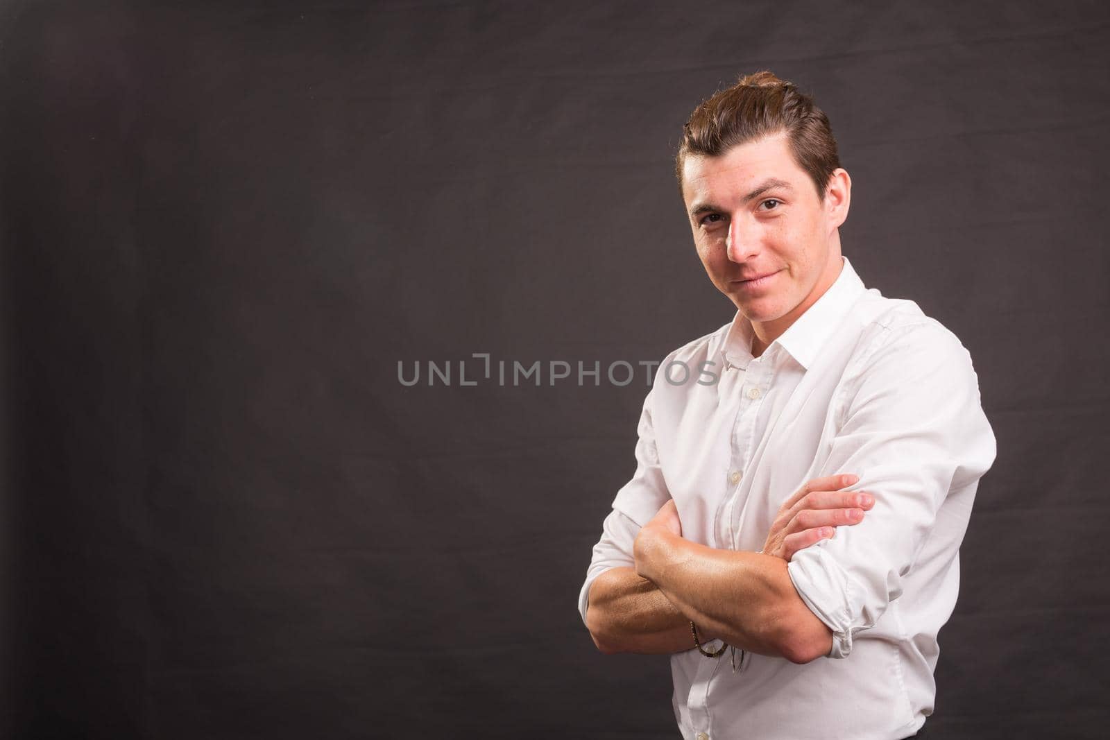 Confident handsome man with crossed arms over gray background with copy space by Satura86