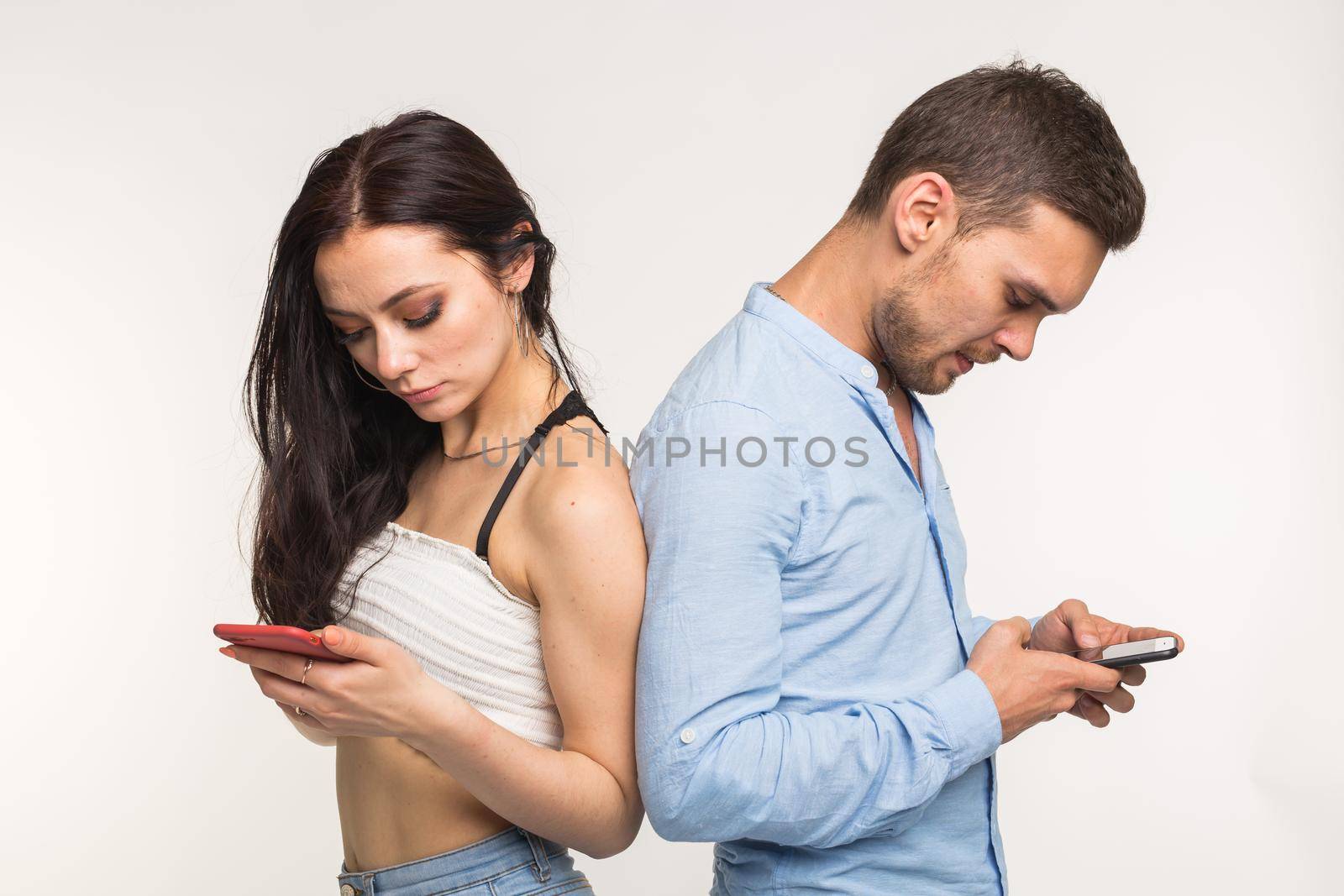 Smartphone addiction concept - Upset couple standing back to each other on white background.