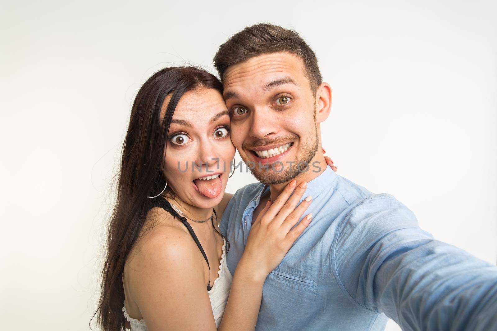 Young attractive couple taking selfie together on white background.