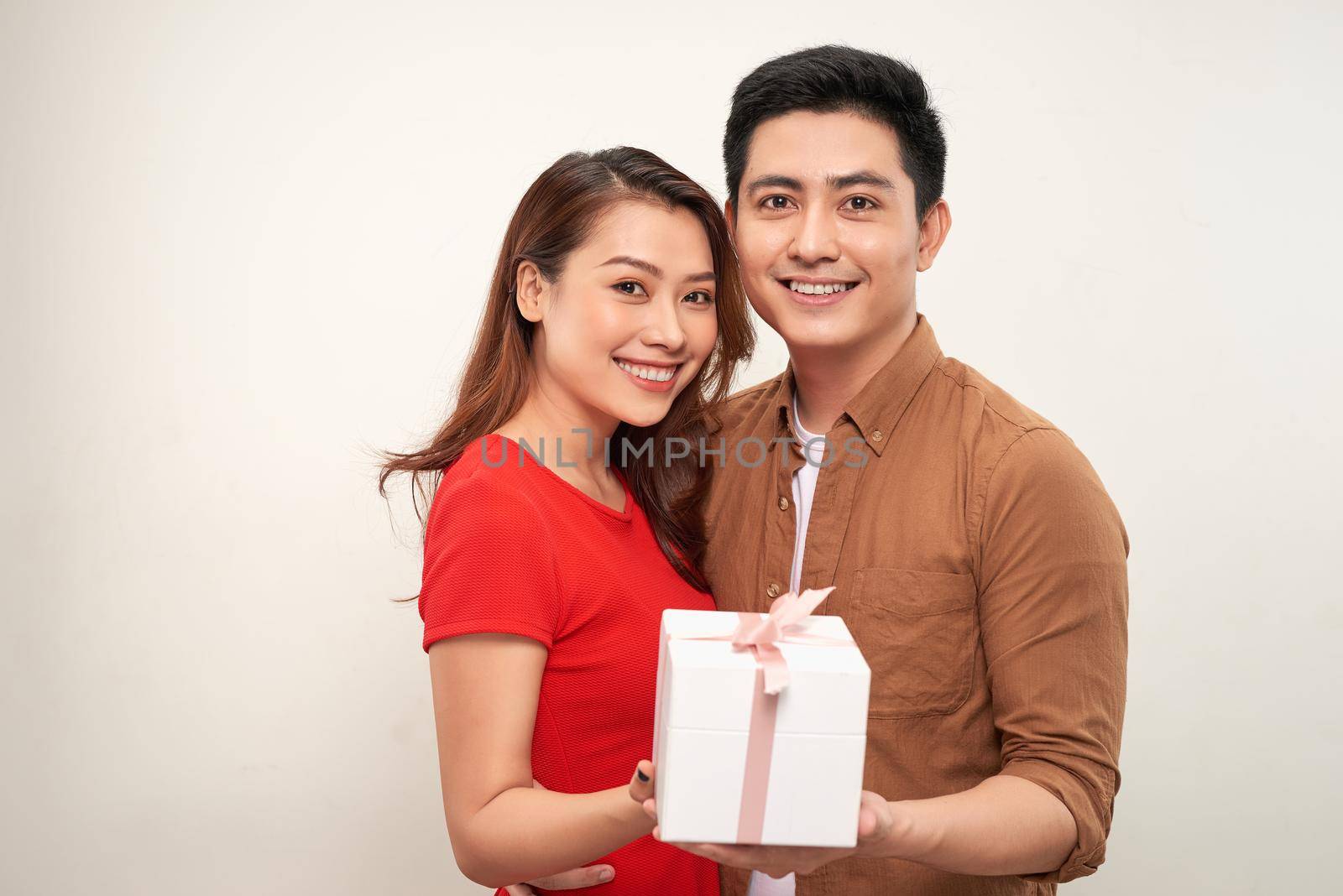 A romantic couple holding a gift isolated on white background by makidotvn