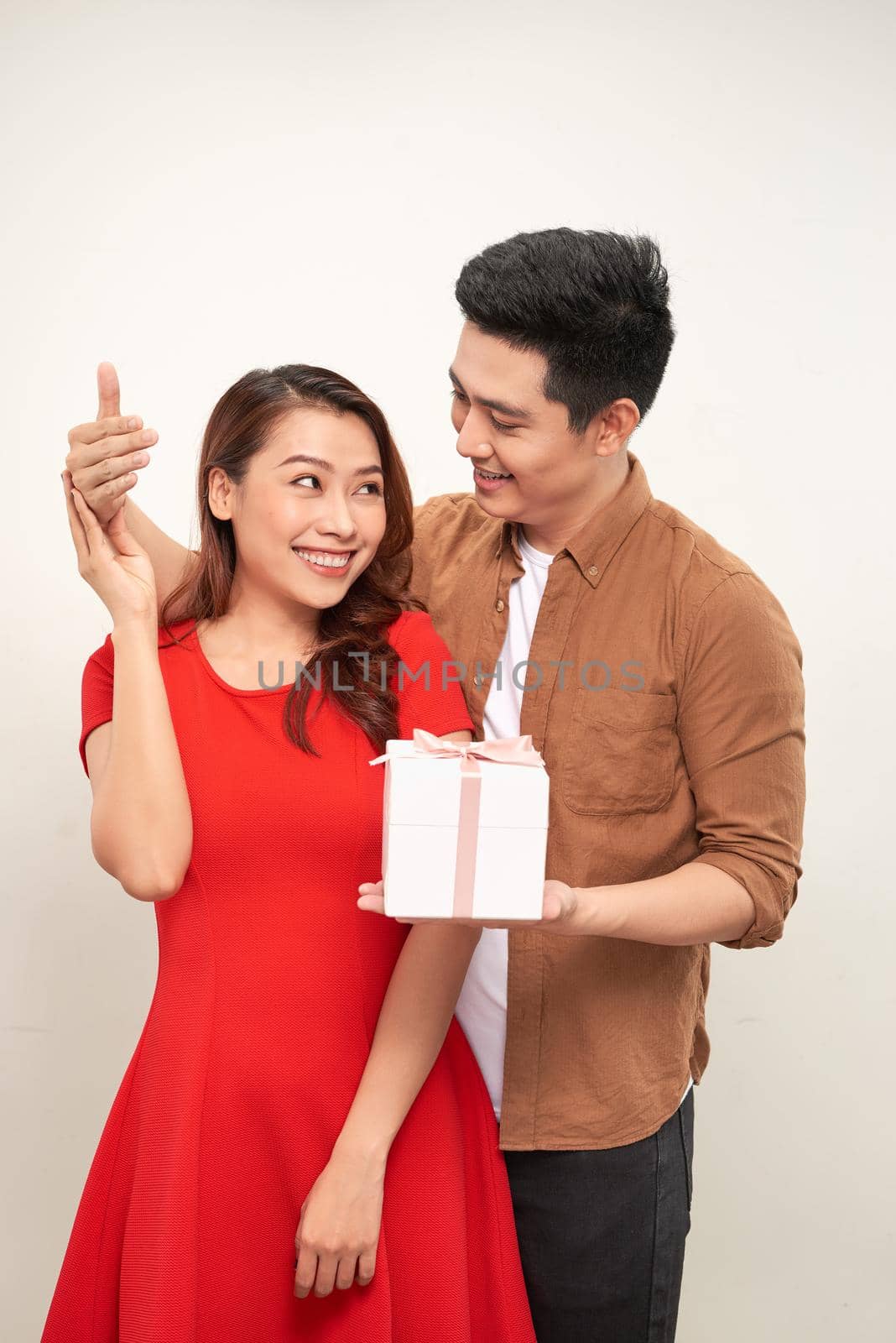 Portrait of an excited young couple holding present box isolated over white background