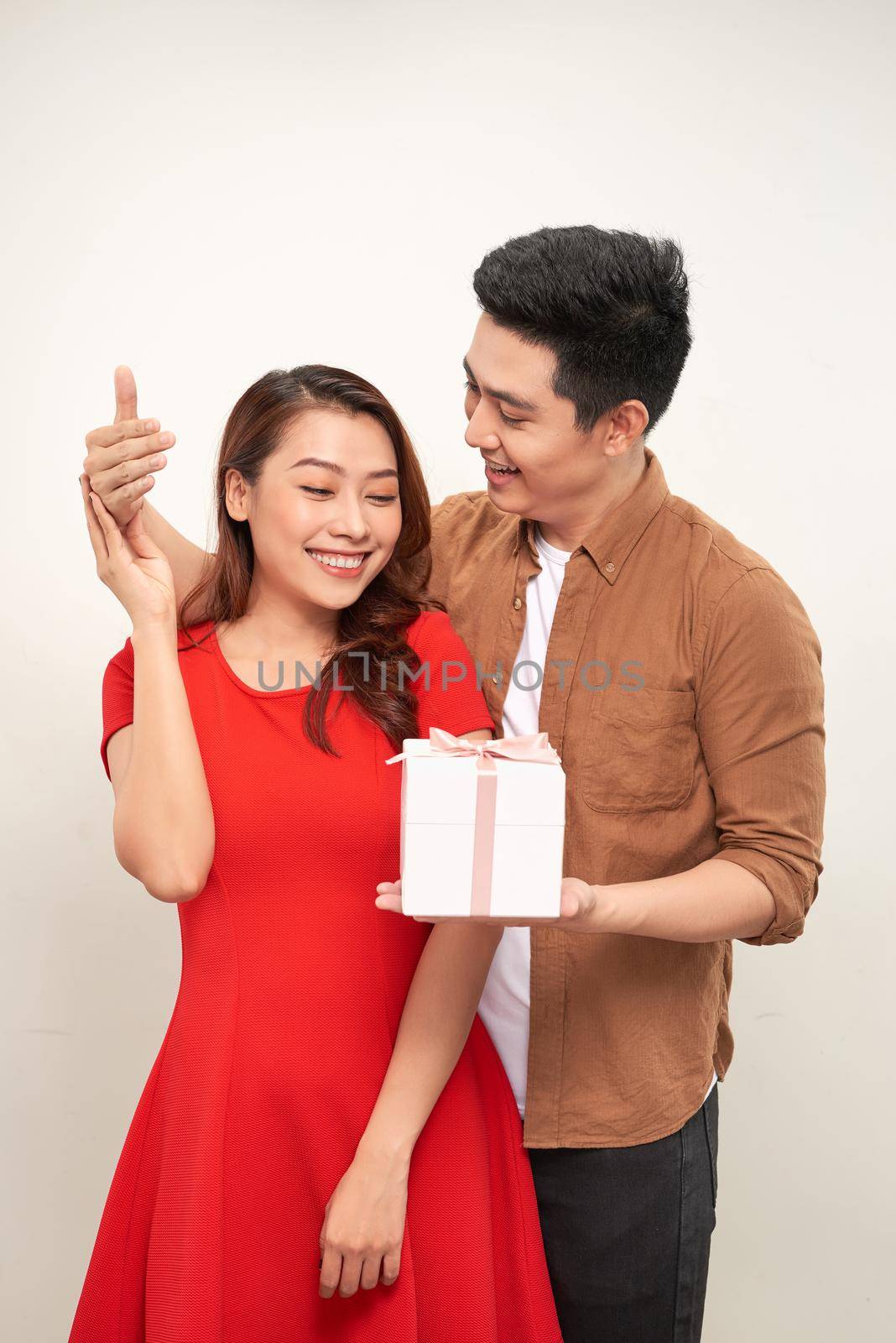 Attractive lovely young couple in love standing together isolated over white background, giving presents, celebrating event