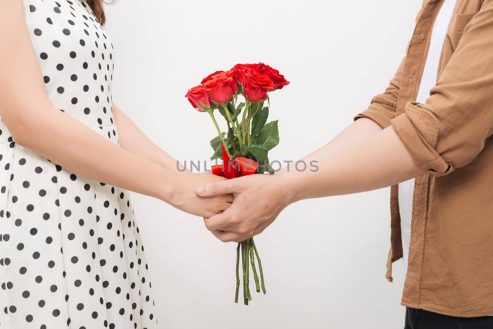 Beautiful young woman hugging her boyfriend and holding nice bouquet of red roses by makidotvn