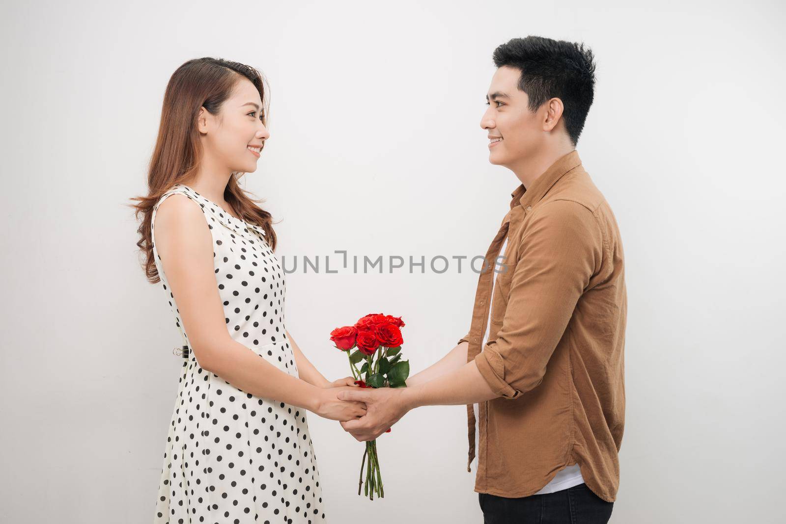 Beautiful young woman hugging her boyfriend and holding nice bouquet of red roses