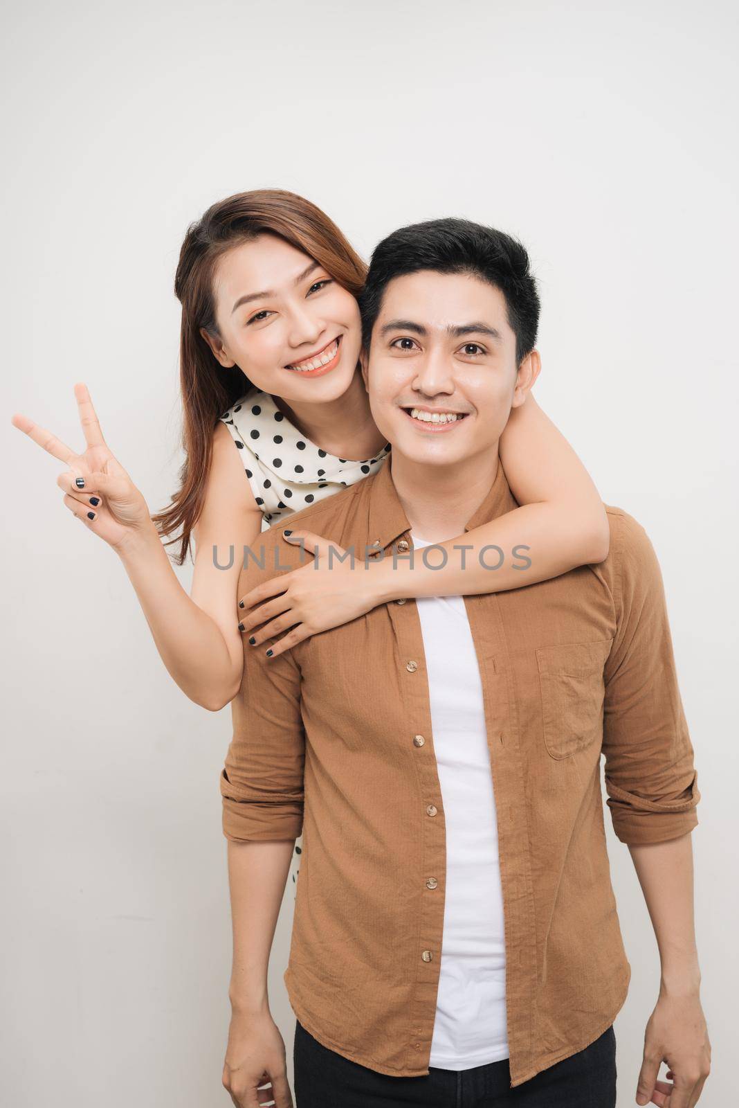 man carrying his lover on back, woman showing peace symbol over white background
