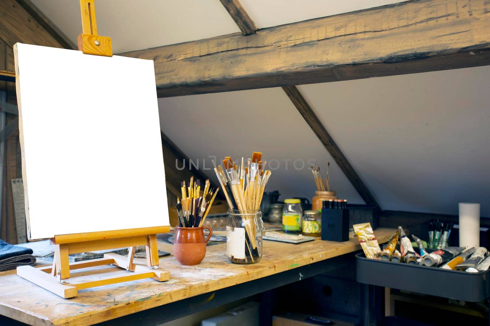 Artistic equipment in a artist studio: empty artist canvas on wooden easel and paint brushes Retro toned photo copy space space for text